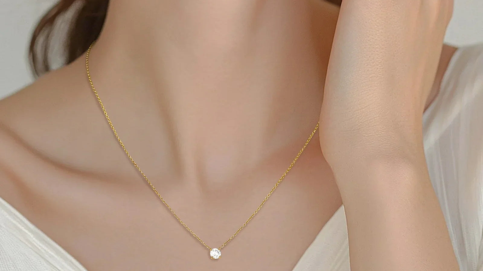 woman wearing a delicate gold necklace with a small, solitaire diamond pendant