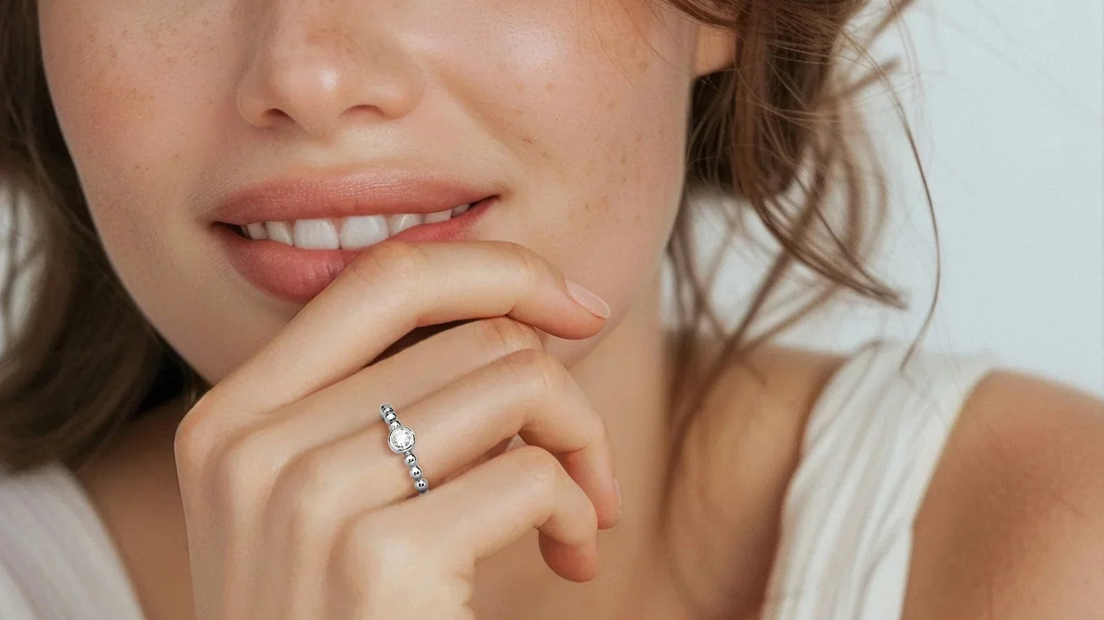 Woman wearing a delicate bezel set diamond ring