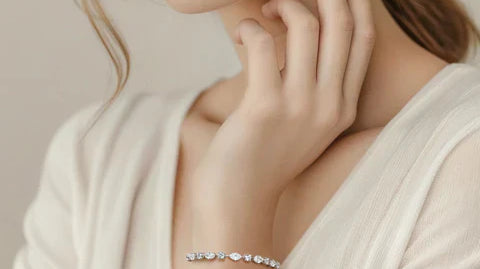 A woman's wrist adorned with a delicate silver bracelet featuring alternating marquise and round diamonds, each secured by a prong setting