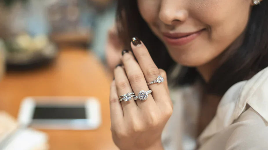 Woman trying on different diamond rings at a jewelry store, comparing styles and sizes