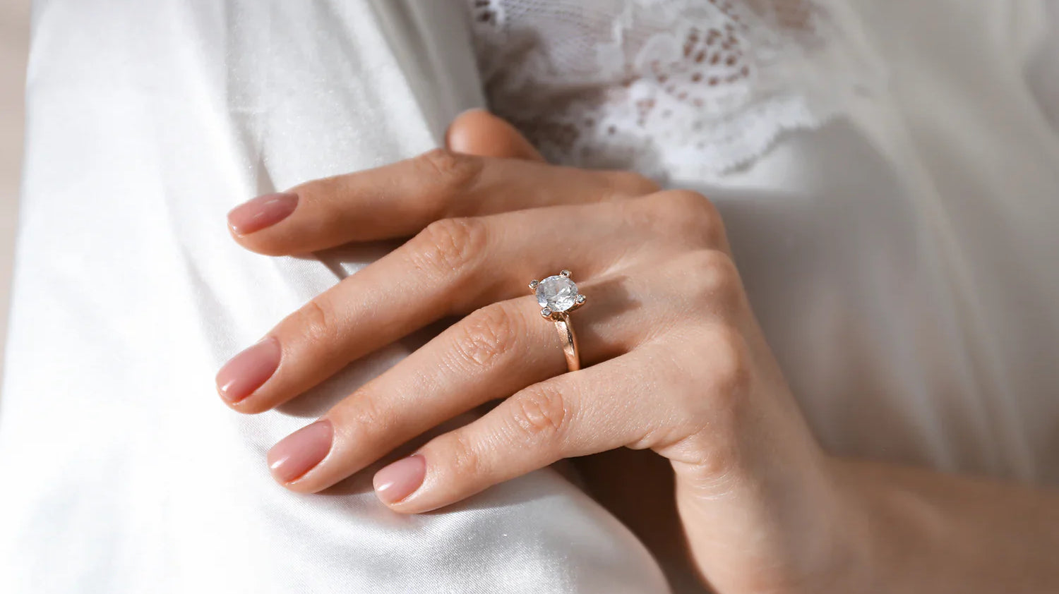 Woman wearing a rose gold solitaire diamond engagement ring on her ring finger