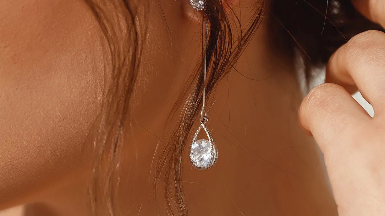 Close-up of a woman wearing delicate, dangling diamond earrings