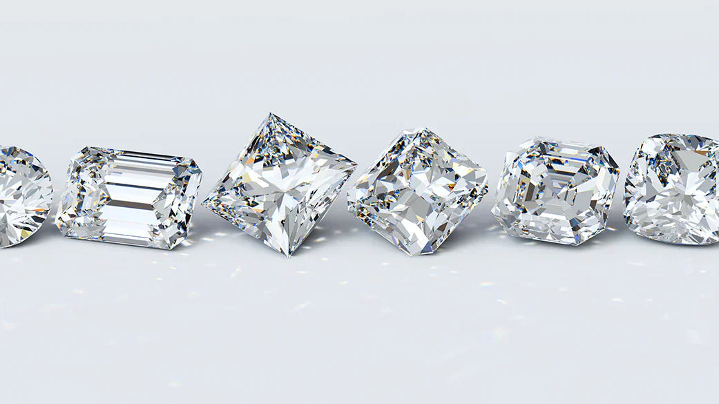 A row of diamonds showcasing different cuts, including round, princess, emerald, and more, highlighting the variety available