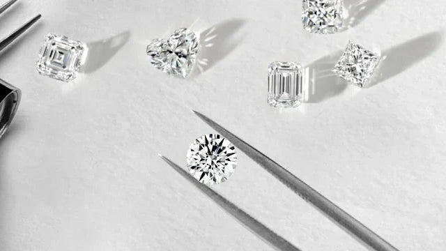 Assorted loose diamonds displayed alongside jeweler's tools on a reflective surface