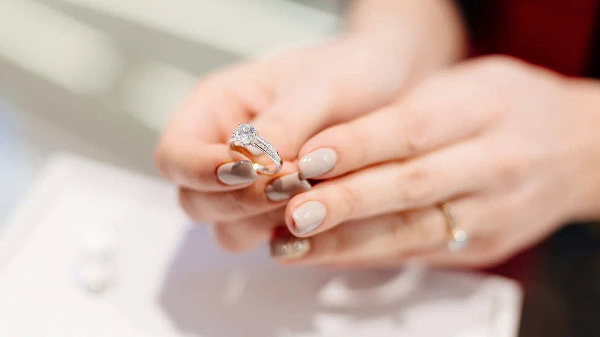 Woman wearing emerald-cut diamond ring with delicate stacked band.