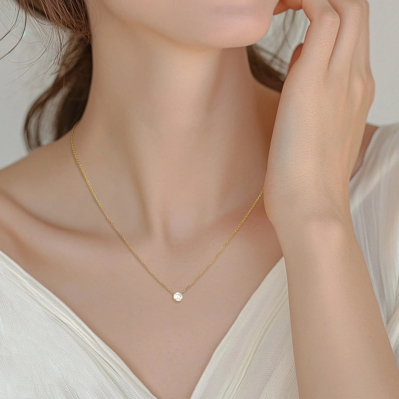  woman wearing a delicate gold necklace with a small, solitaire diamond pendant