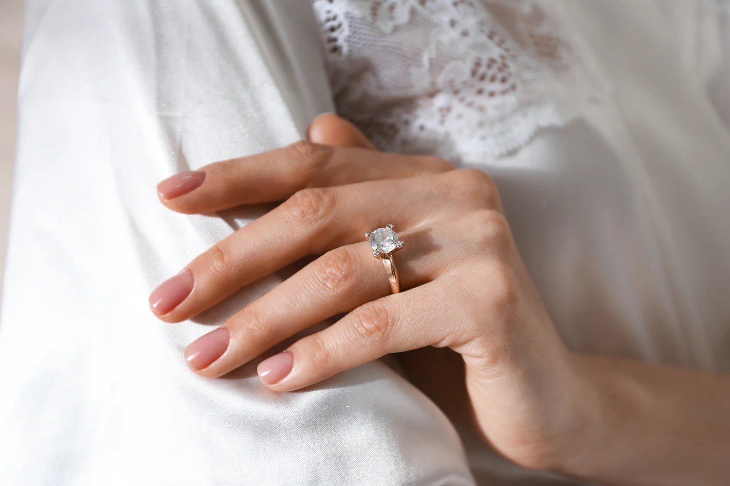 Woman wearing a rose gold solitaire diamond engagement ring on her ring finger