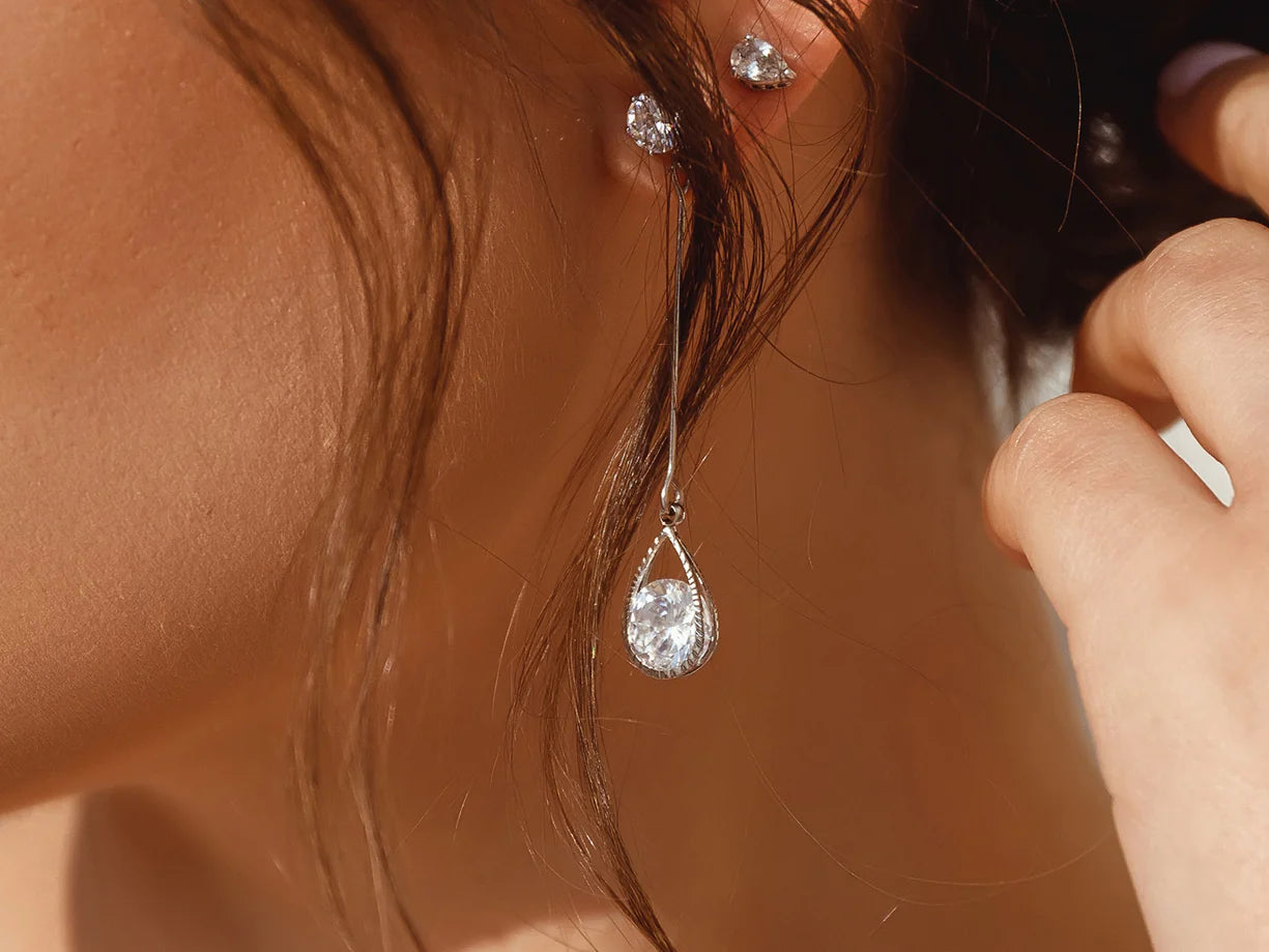 Close-up of a woman wearing delicate, dangling diamond earrings