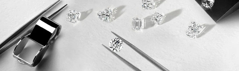 Assorted loose diamonds displayed alongside jeweler's tools on a reflective surface