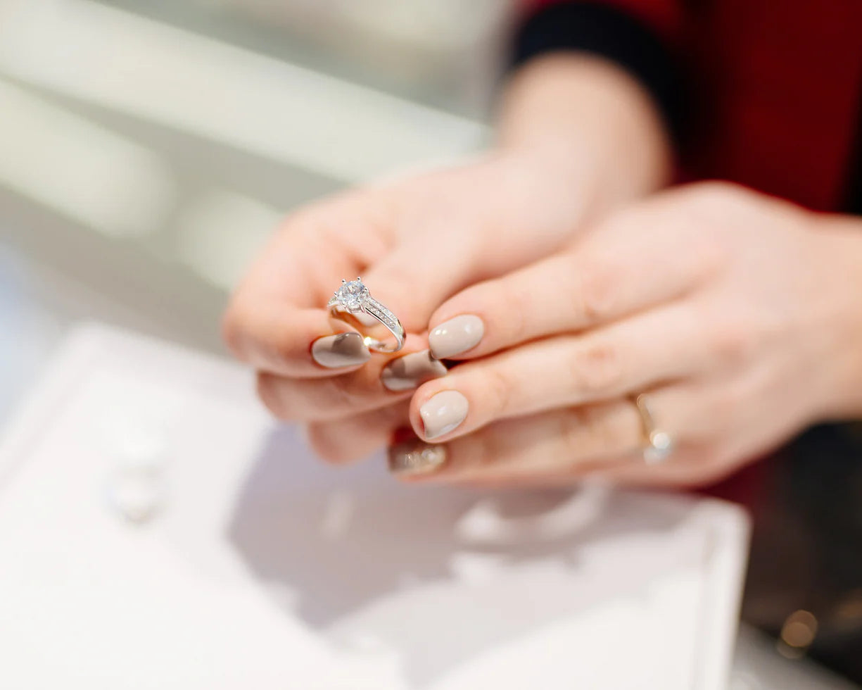 Woman wearing emerald-cut diamond ring with delicate stacked band.