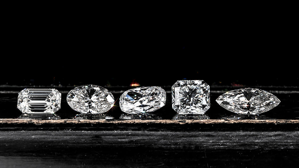 Five lab diamonds of different shapes and sizes on a dark background