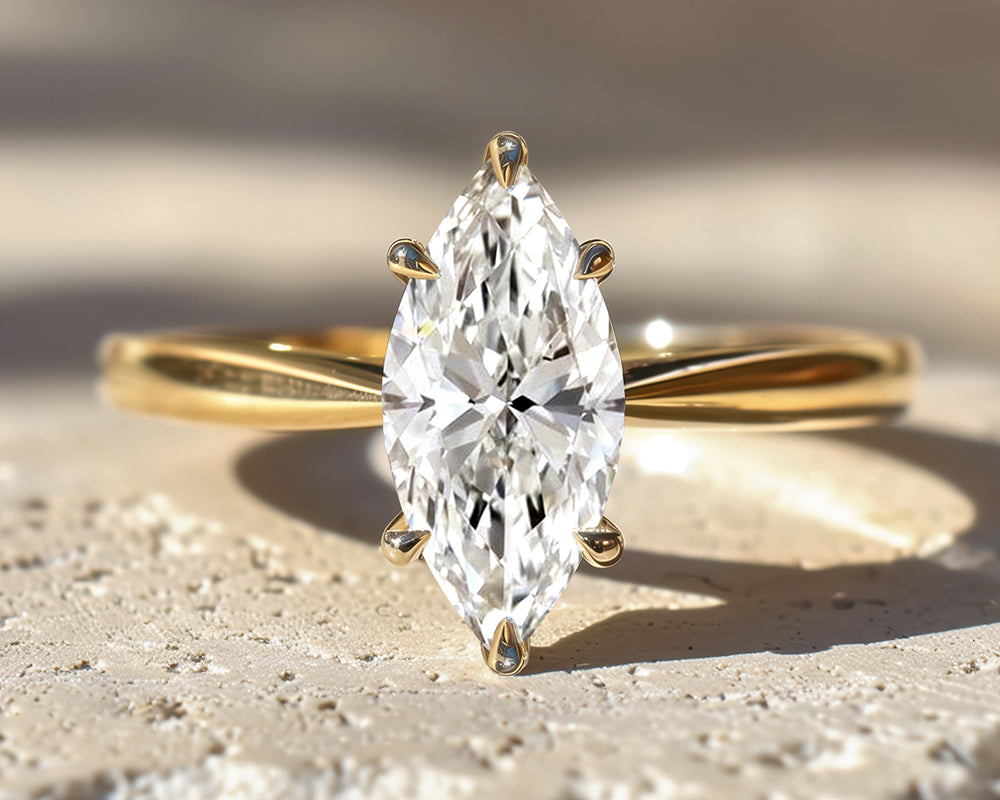 Gold ring with a marquise-shaped lab grown diamond on a textured surface