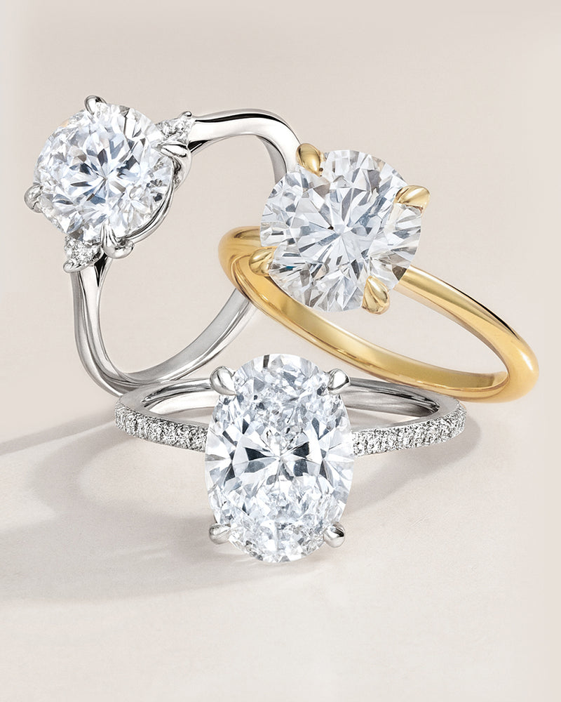Three lab diamond engagement rings in white gold and yellow gold on a beige background