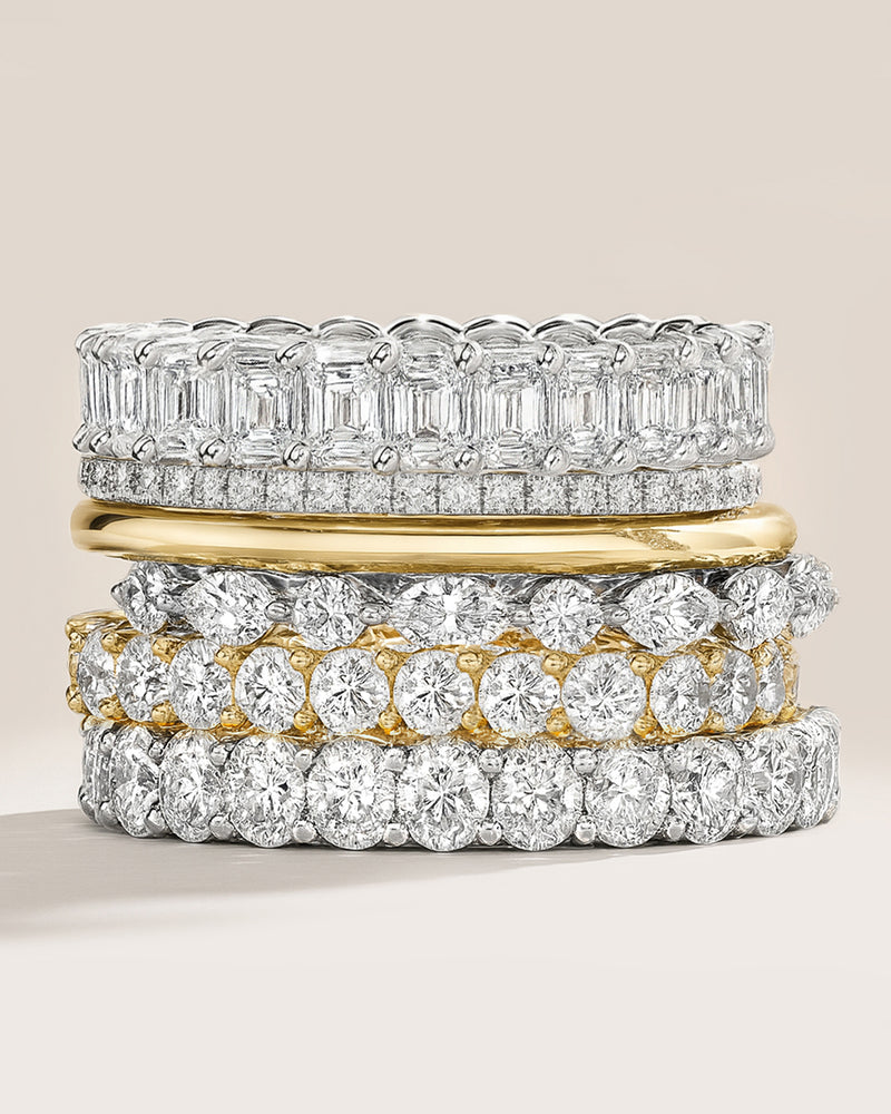 Stack of lab diamond rings with different designs on a light background