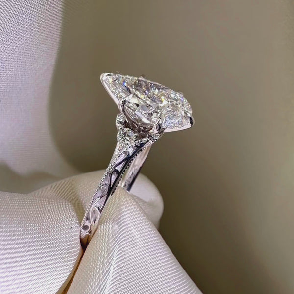 Side profile of a pear-cut diamond engagement ring featuring a vintage-style filigree band with milgrain edges in polished white gold.