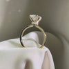 Side view of a round-cut diamond engagement ring featuring a hidden halo and a cathedral-style yellow gold band.