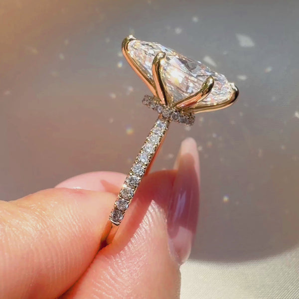 Side profile of a pear-cut diamond engagement ring featuring a hidden halo, a four-prong yellow gold setting, and a sparkling pavé-set diamond band.