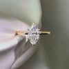 Marquise-cut lab diamond engagement ring featuring a six-prong setting on a polished yellow gold band, displayed against a white satin background.