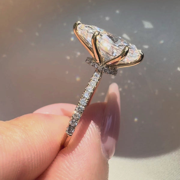 Side profile of a pear-cut diamond engagement ring featuring a hidden halo, a four-prong yellow gold setting, and a sparkling pavé-set diamond band.