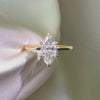 Marquise-cut lab diamond engagement ring featuring a six-prong setting on a polished yellow gold band, displayed against a white satin background.
