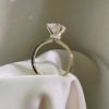 Side view of a round-cut diamond engagement ring featuring a hidden halo and a cathedral-style yellow gold band.