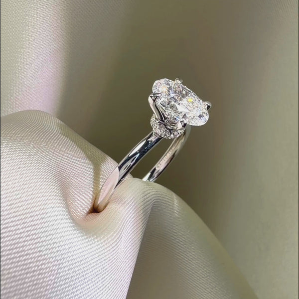Side profile of an oval-cut diamond engagement ring featuring a hidden halo and a diamond-encrusted basket on a polished white gold band.